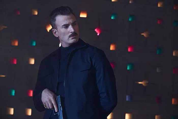 Actor Chris Evans stands holding a gun in the movie The Gray Man.