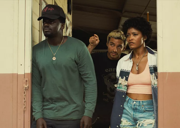 Two men and a woman stand in a doorway and look up at the sky.