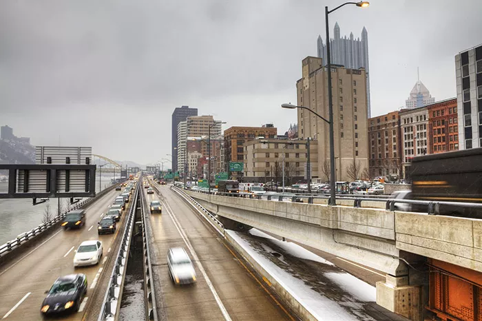 Lines of cars on the highway drive away from the Downtown skyline