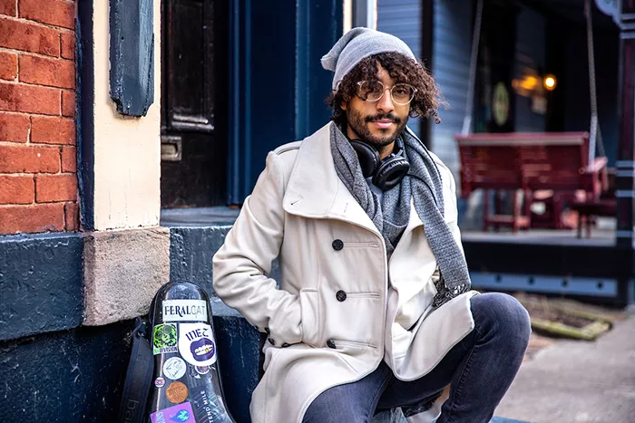 Pittsburgh musician F3ralcat sits outside and wears a light tan coat.