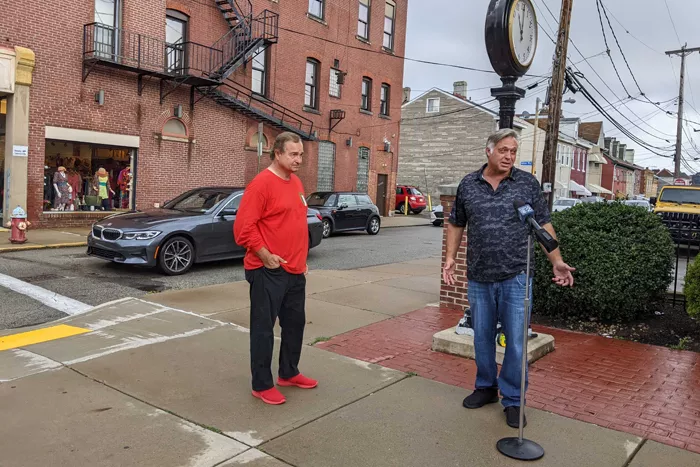 Two men stand on a street corner during a press conference in the Bloomfield neighborhood of Pittsburgh