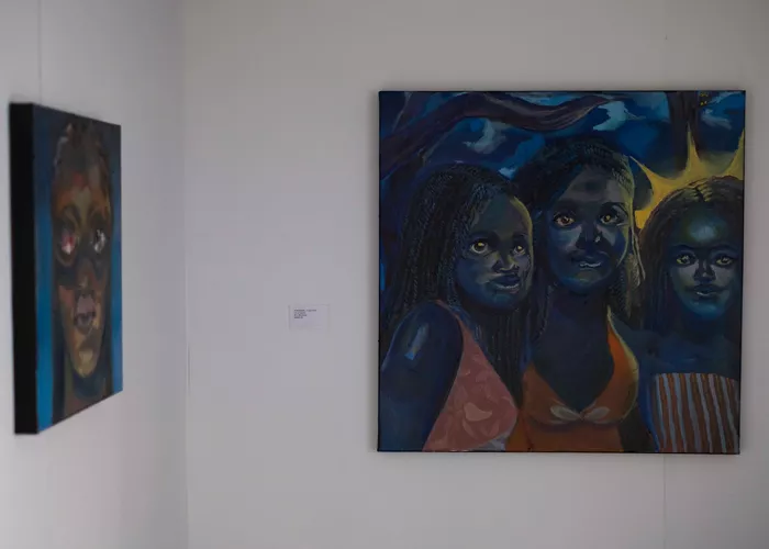 A blue painting depicting three smiling Black women hangs as part of the exhibition Dream of a Black Planet.