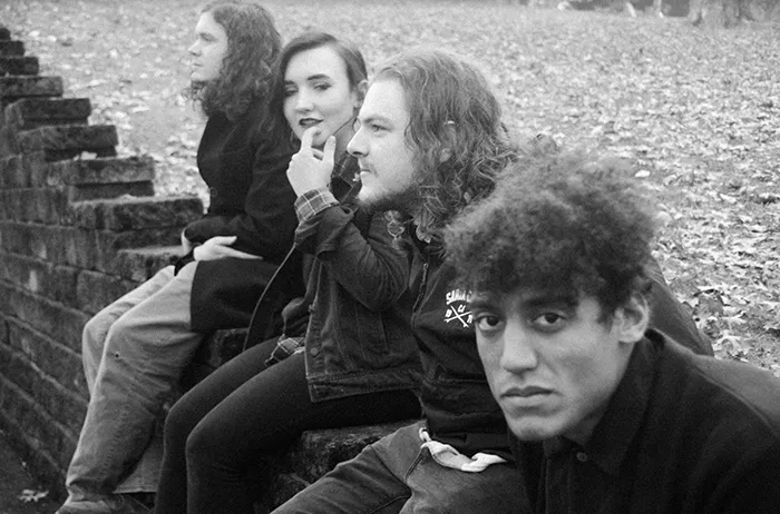 Black-and-white photo of four people sitting on a brick wall