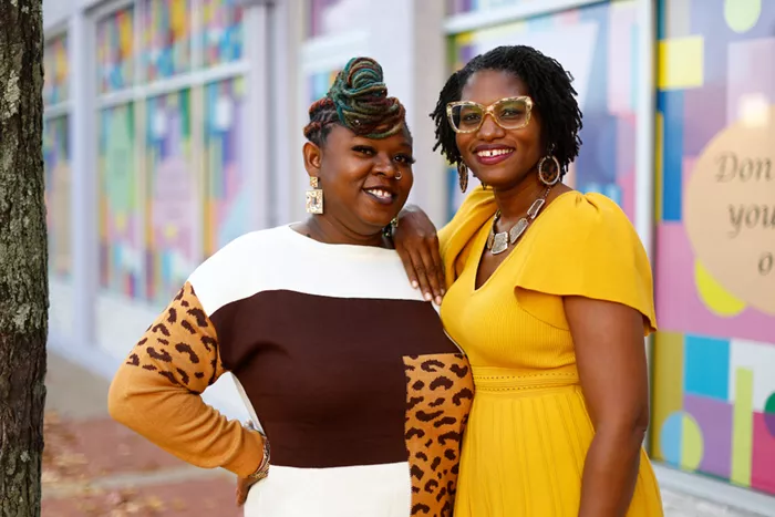 Two women stand together on the sidewalk