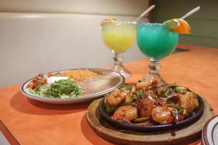 A fajita and two margaritas are shown on a table inside a restaurant