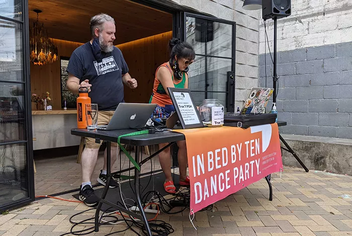 Two DJs oversee a turntable during In Bed By Ten at Trace Brewing