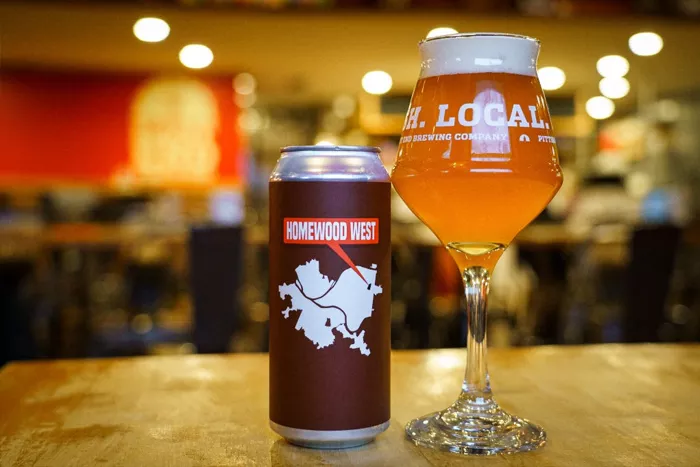 A can with a specially designed label sits next to a tall glass filled with foamy beer.