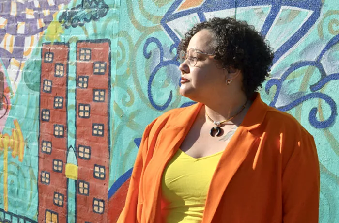 A woman wears a orange suit with a yellow shirt