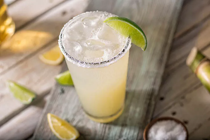 Overhead shot of a frozen margarita surrounded by lime wedges and a small bowl of salt.