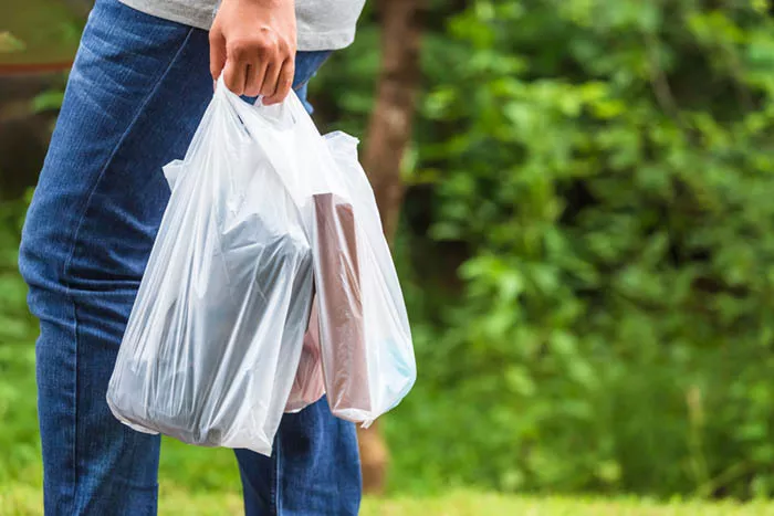 A shot of a person holding two white plastic bags.