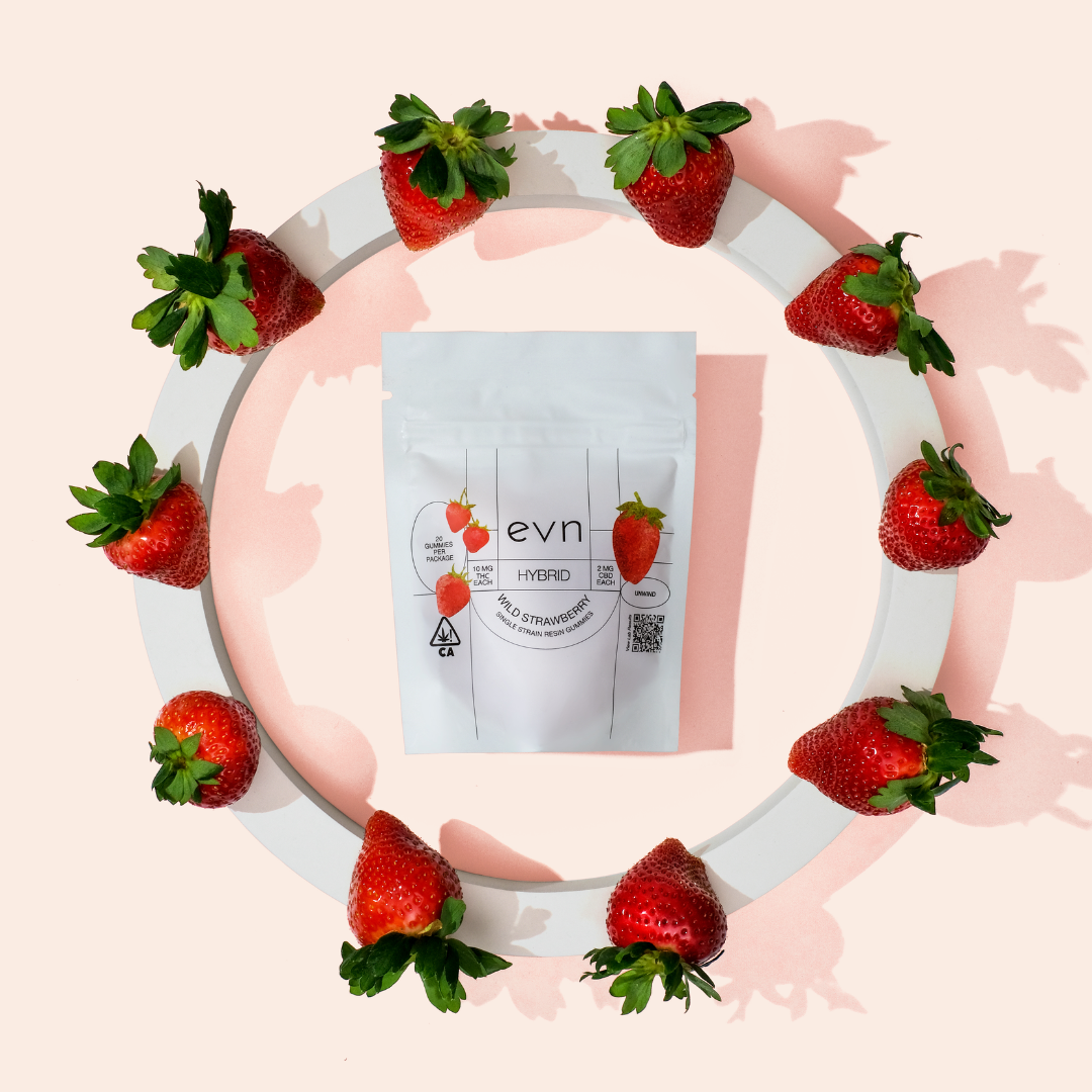 Photo of white evn gummy bag laying on pale pink background, surrounded by a ring of strawberries. Label reads 
