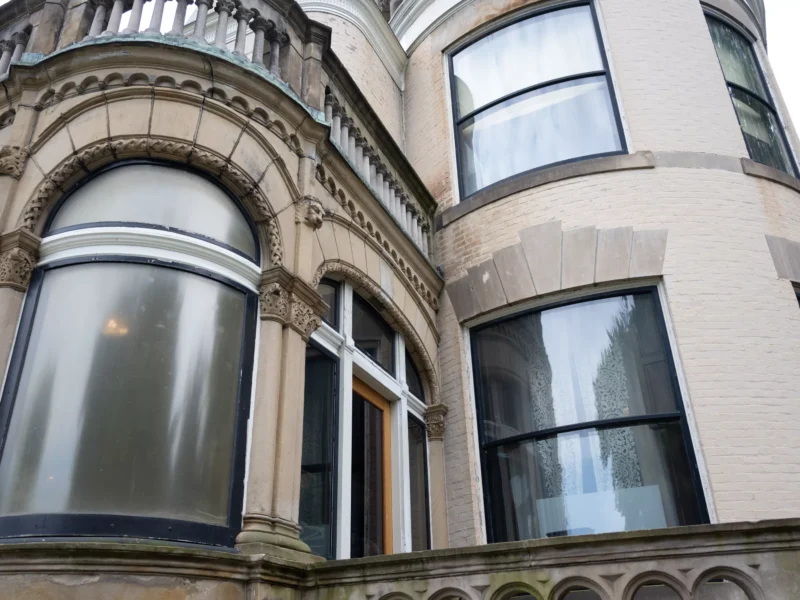 Curved and stained glass windows adorn the intricate brick façade of a mansion