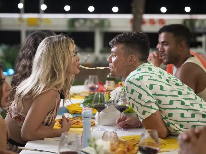 A young woman and man eat a spaghetti noodle from opposite ends