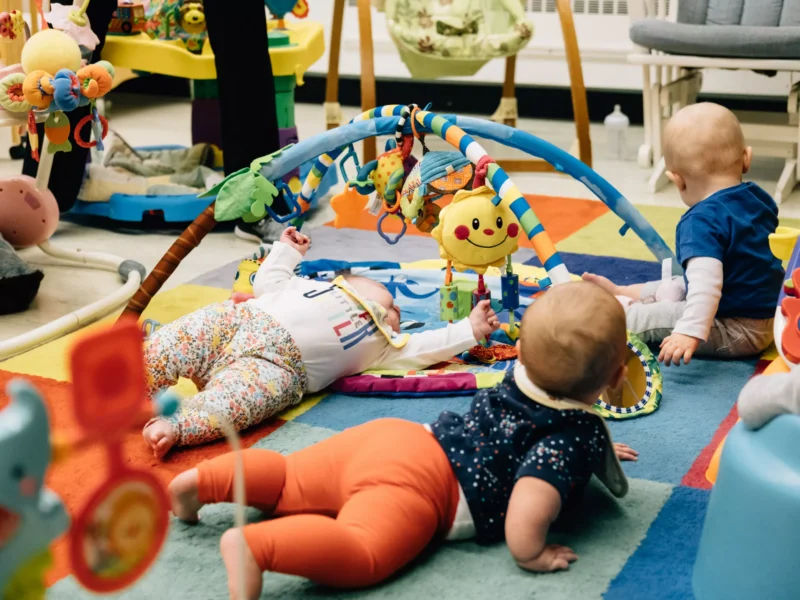 Babies crawl amid colorful toys and soft carpeting
