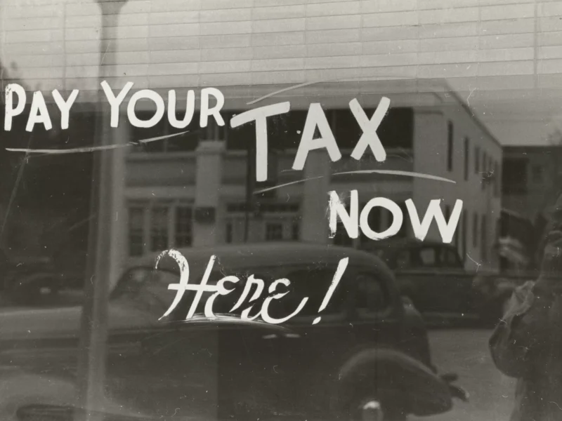 An old photograph of a window reading "Pay your tax now HERE!"