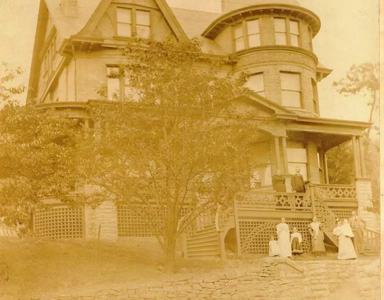 A sepia photo of a Victorian mansion with a large pointed turret