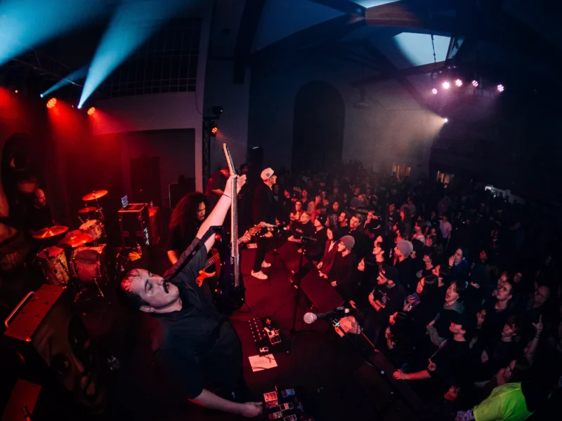 A band stands amid a seething crowd on a lit stage