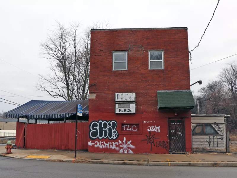 A neglected two-story brick building with faded sign, awning, and graffiti