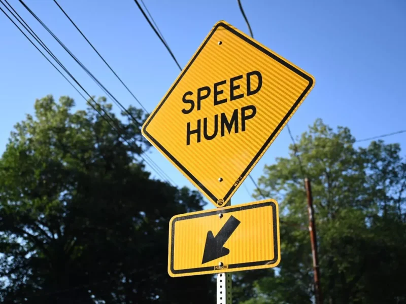 A diamond-shaped yellow sign pointing to a speed hump