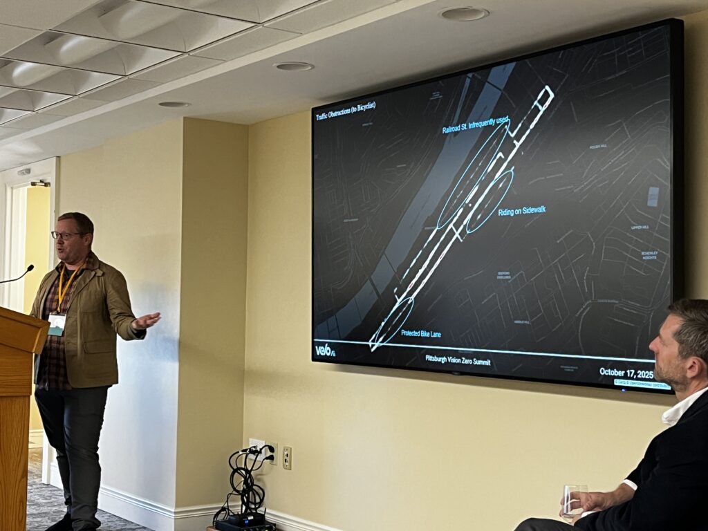 A man in untucked shirt and chinos shows a street grid with hot spots for safety risks