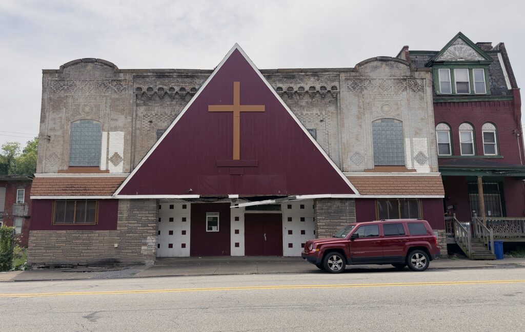 An art deco façade overbuilt with a large gable with a cross on it
