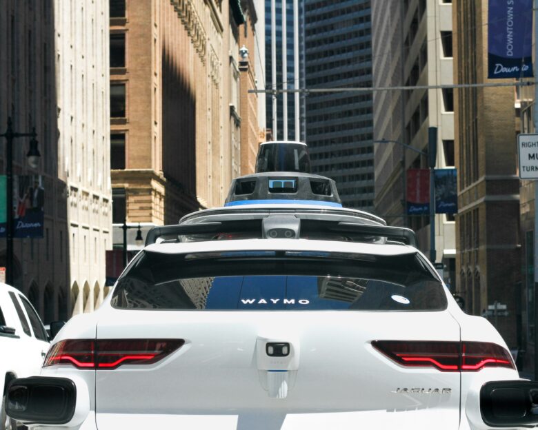 A Waymo autonomous vehicle amid 20th century skyscrapers